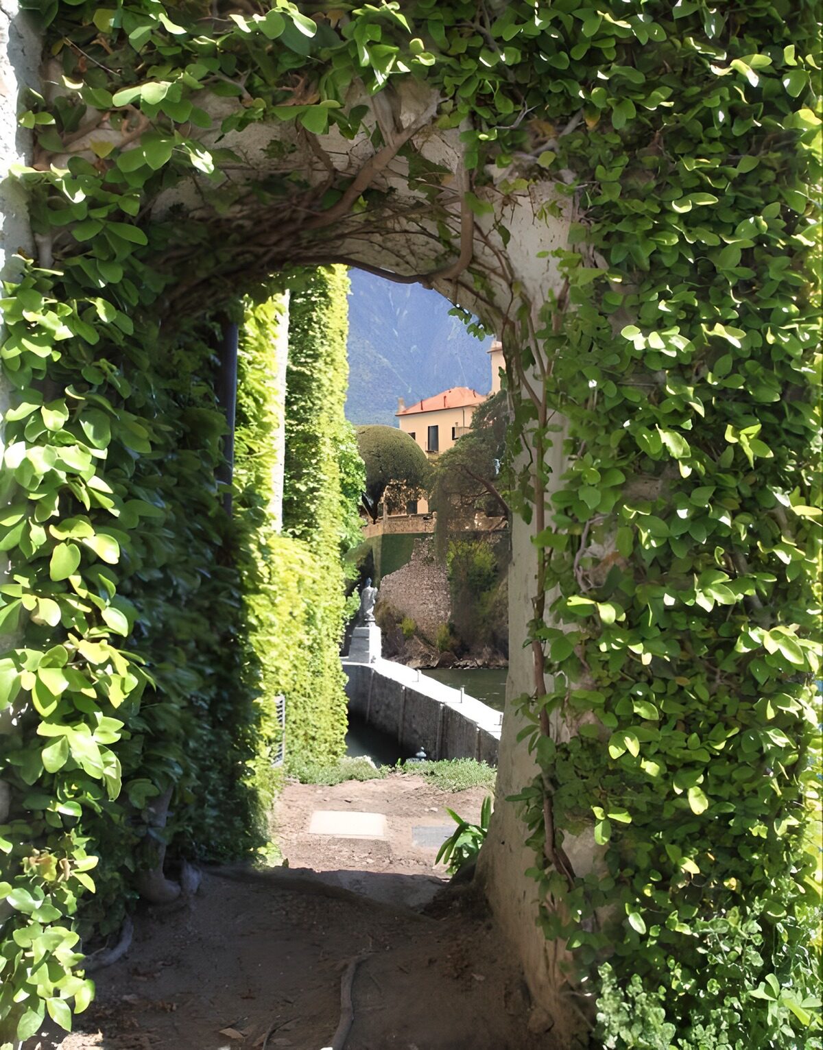 OCUK61902: Sand covered passage way and an arched brick wall covered with ivy