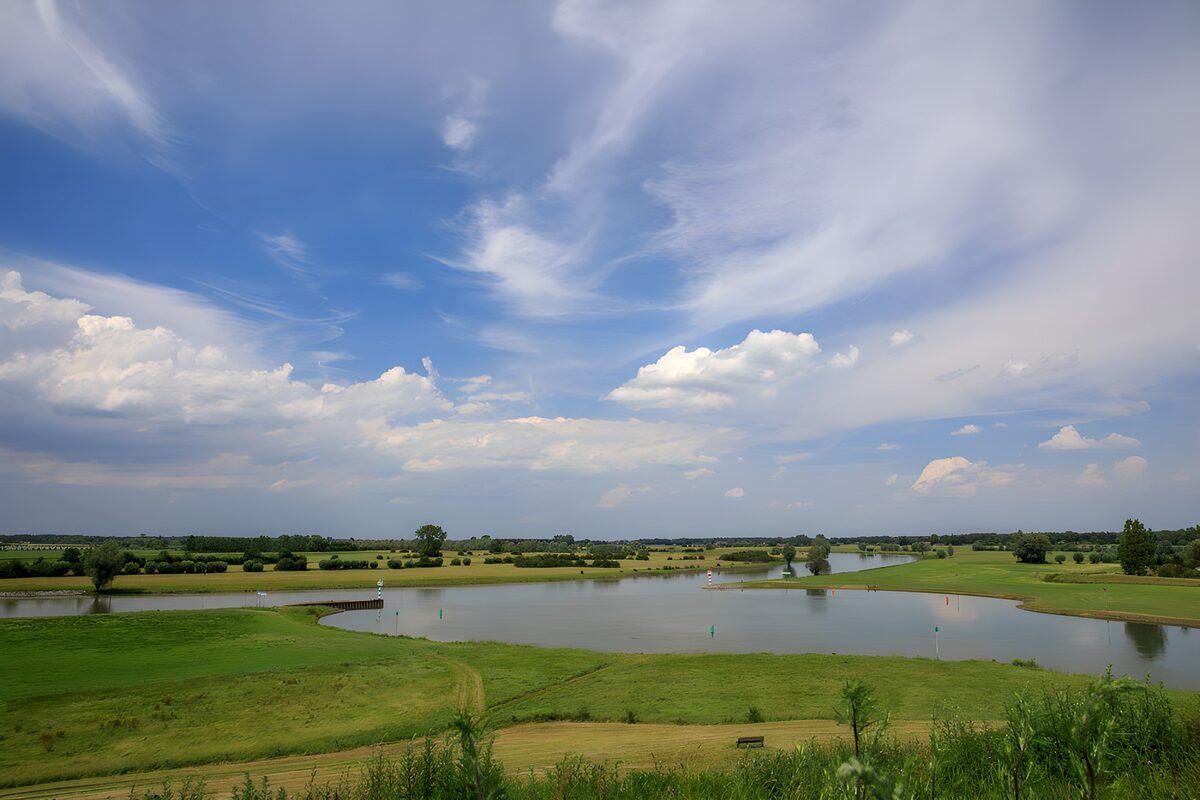 OCUK10600: Tranquil River Landscape Under Blue Skies