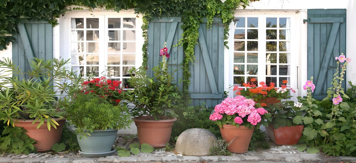 French facade with flowers, windows, cans and blue shutters