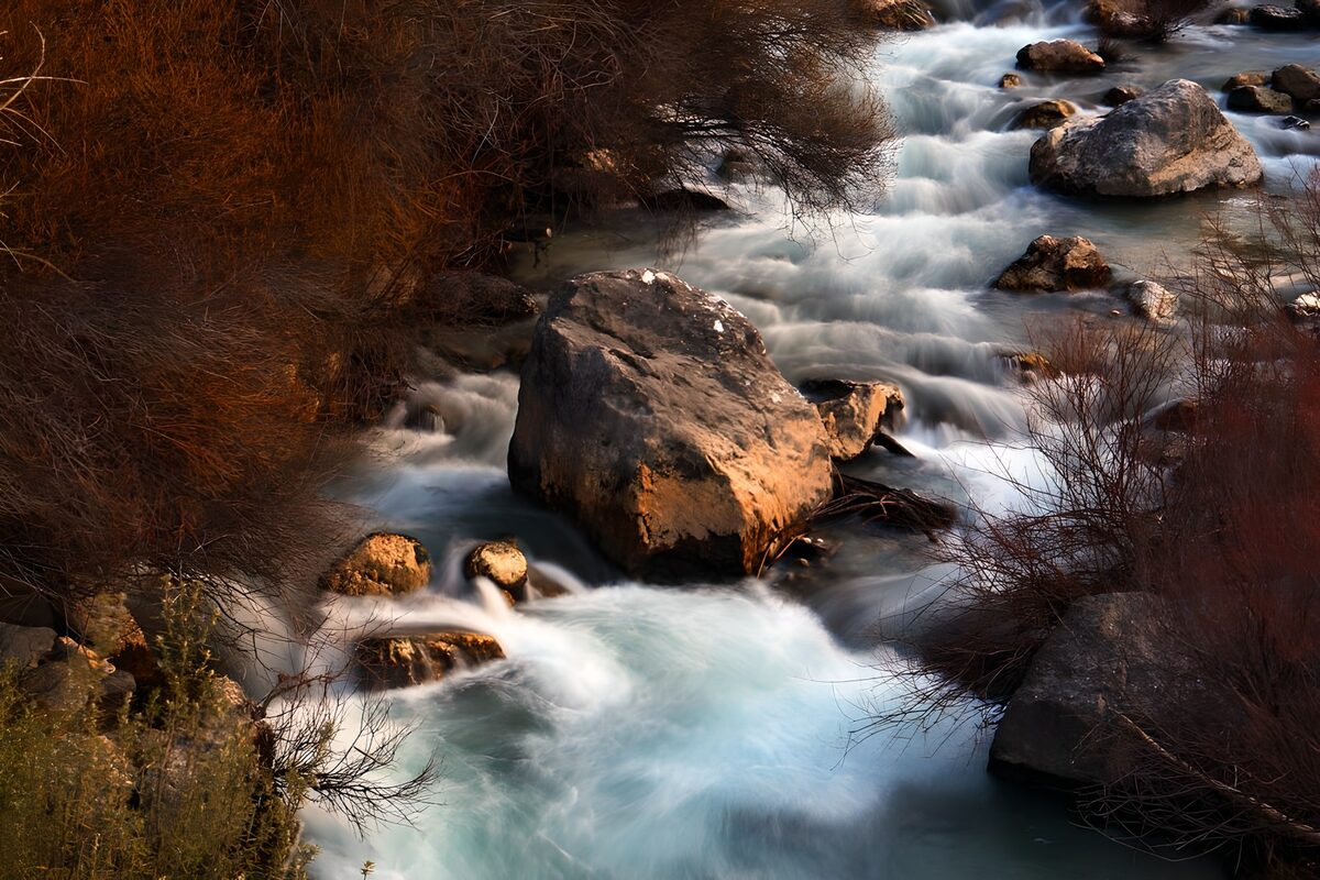 OCUK77015: Serene River Flowing Through Rocky Landscape