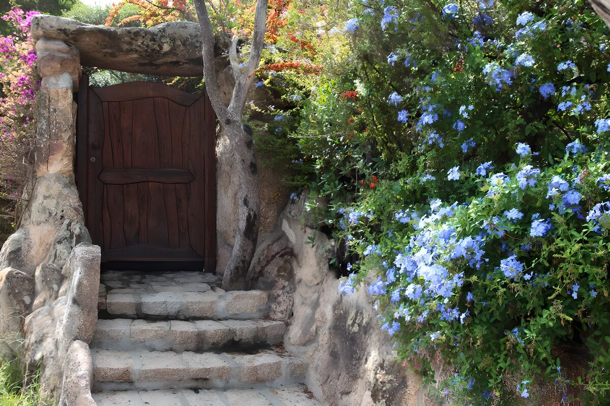 OCUK33734: Dark wooden door in garden next to blue flowers