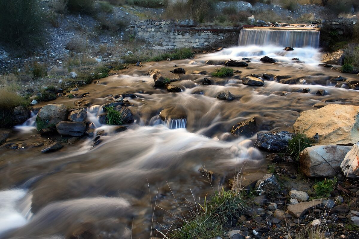 OCUK66183: Serene Stream Flowing Through Rocky Terrain