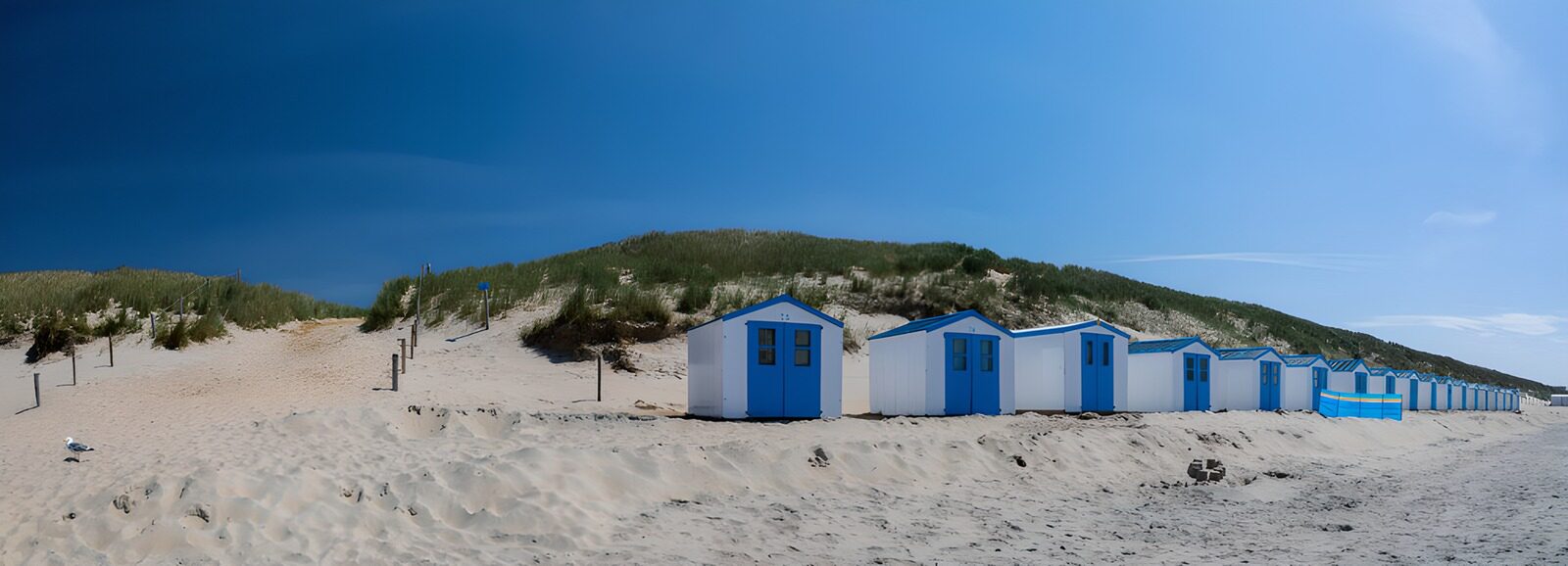 OCUK76737: Coastal Beach Huts Under a Blue Sky