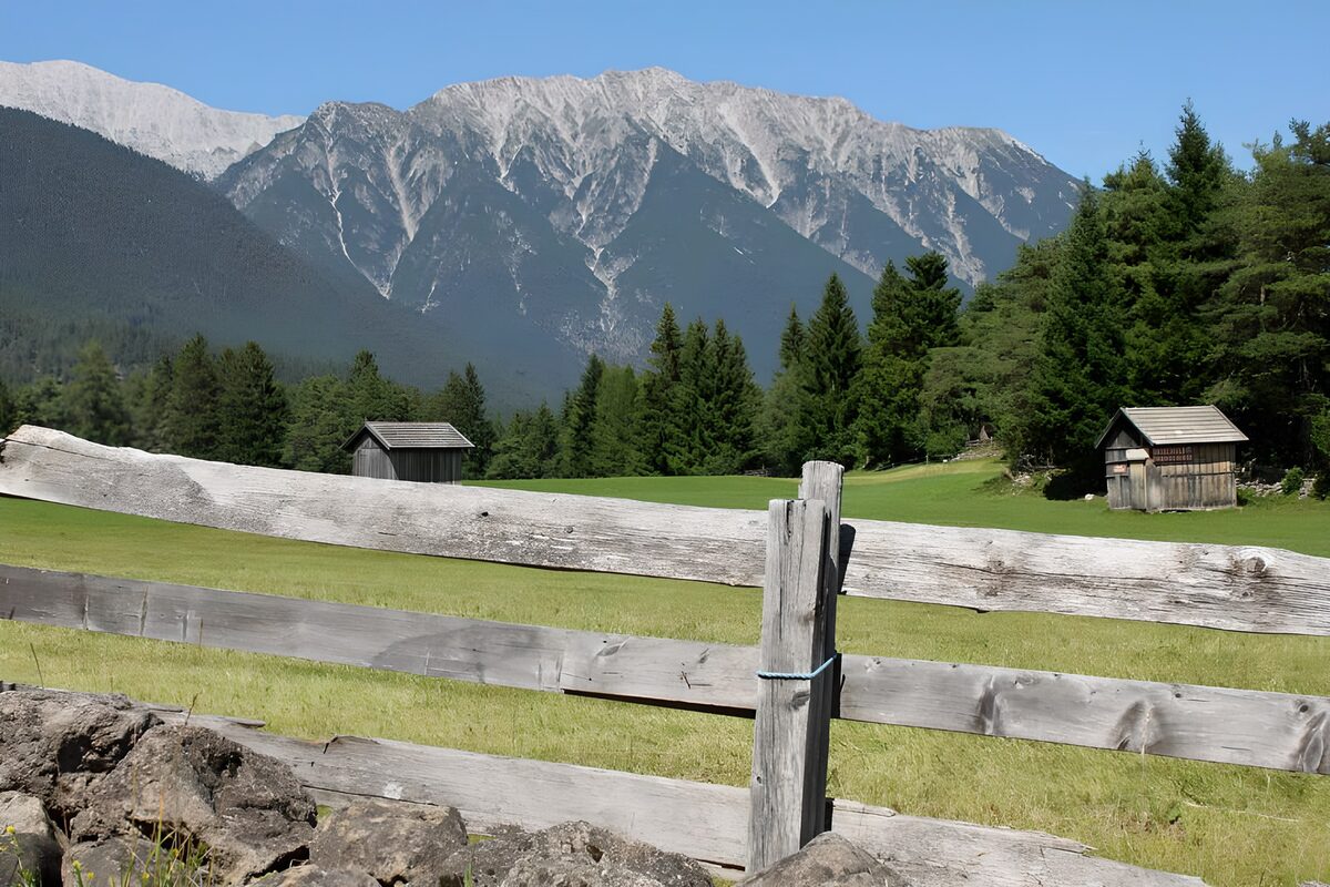 OCUK90931: Stables behind gate in alpine meadow
