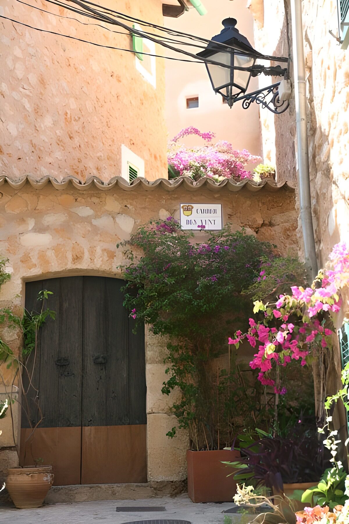 OCUK76506: Large door in stone wall with lantern and plants 1