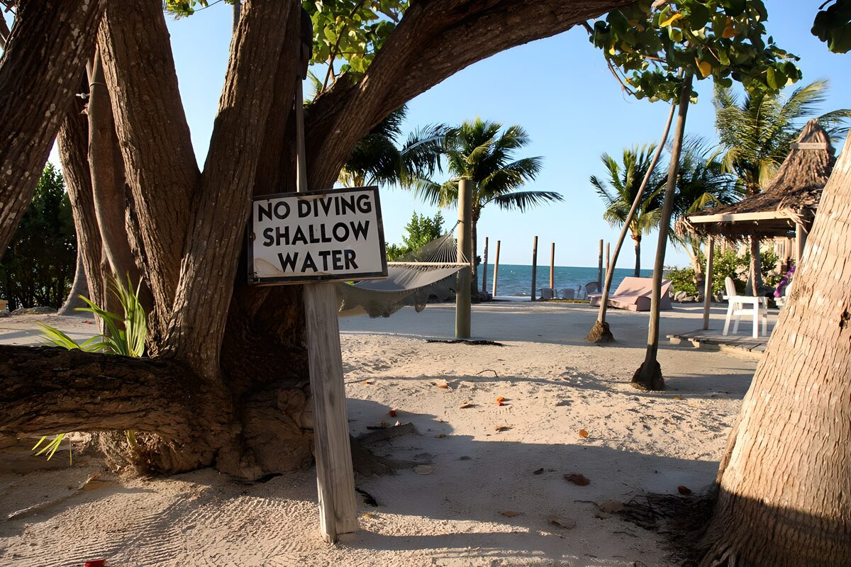 OCUK21032: Caribbean beach with 'no diving shallow water' sign