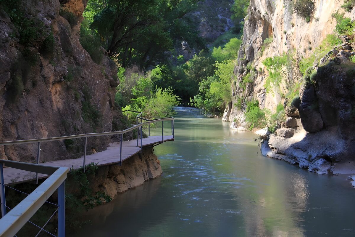 OCUK50750: Serene River Amidst Majestic Cliffs