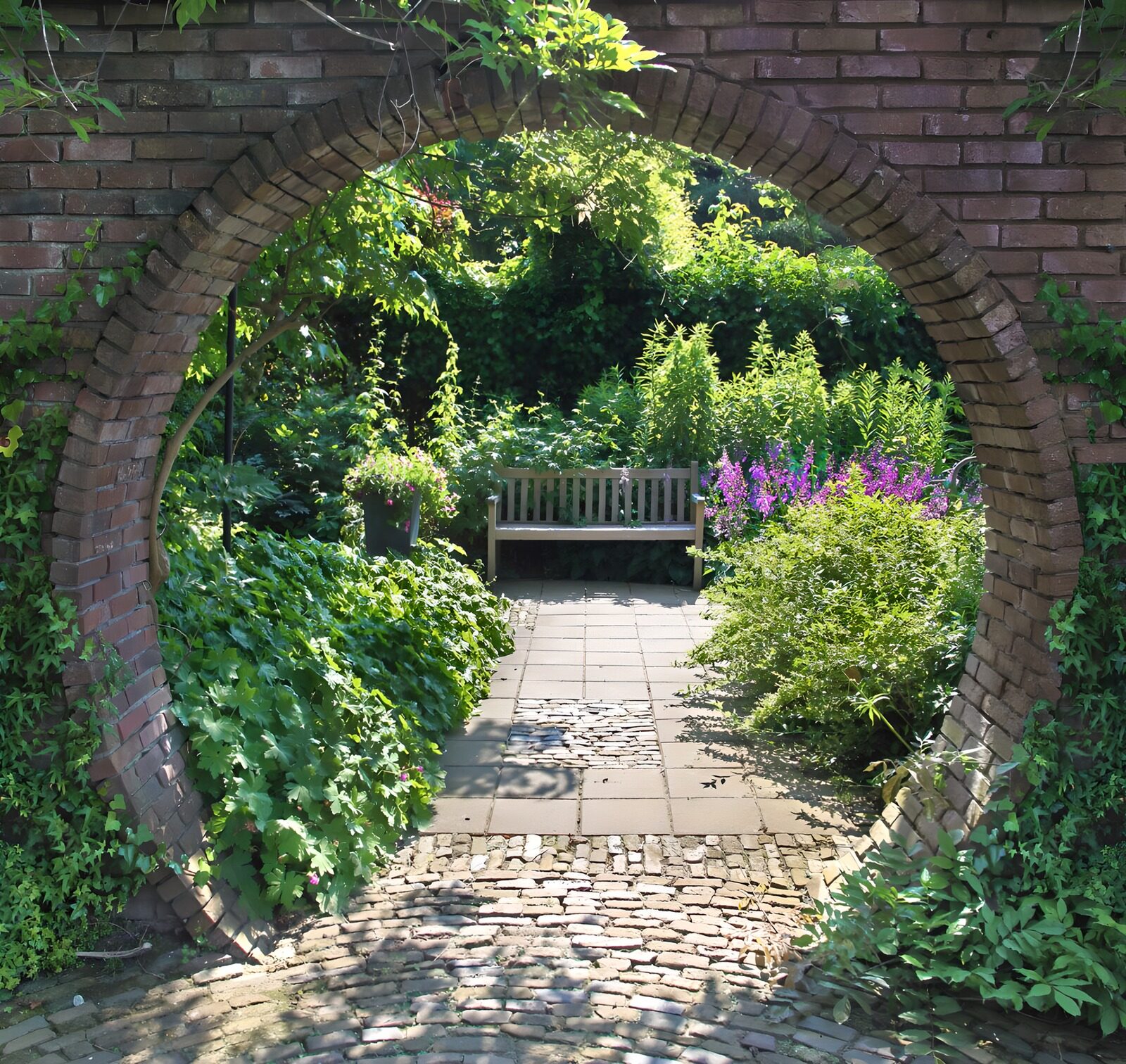 OCUK71945: Round access in brick wall looking at a bench near flowers and plants